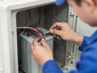 Technician replacing a capacitor inside an air conditioning unit